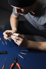 Man, watchmaker in hat repair pocket watch with screwdriver. Craft, hand made work background