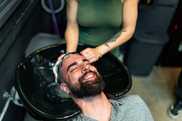 A male client enjoys a relaxing hair wash in a stylish barber shop, enhancing his grooming...