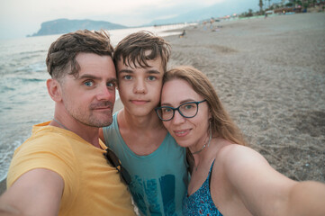 Happy family taking a photo on a beach at the sea in Alanya city, Turkey. Travelling or vacation concept