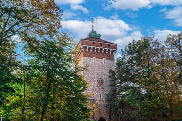 Low angle view of 14th century Gothic tower, Saint Florian Gate (Brama Florianska), against a blue sky with clouds, UNESCO World Heritage Site, Karakow, Poland