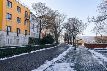 Buda Castle with buildings next to cobblestone pathway in winter with melting snow around, Budapest, Hungary