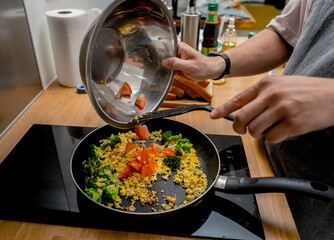 Chef at the kitchen preparing tofu scramble with vegetables