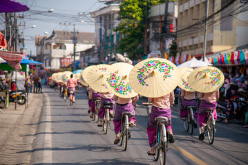 Women holding beautiful umbrellas and cycling. show at Bosang umbrella festival Chiang Mai, Thailand....