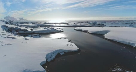 Aerial Antarctica ocean bay coastline winter landscape. Snow-covered rocky island under bright sun blue sky. Untouched wilderness of Arctic nature, mountain in background. Explore travel to South Pole