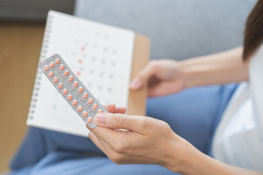 Contraception, menstruation and pregnancy concept, birth control pills asian young woman holding hormonal oral contraceptive pills with calendar, menstrual cycle. Prevention, safe virus sex disease.