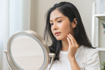 Anti aging beauty, happy asian young woman looking in mirror reflection at home, touching face skin...