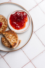 Hot Toasted Crumpets with piece of butter on a plate with strawberry jam. Perfect tasty breakfast popular in England, UK