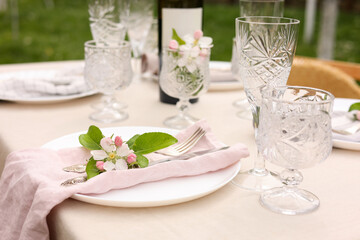 Stylish table setting with beautiful spring flowers, wine, plates and glasses in garden