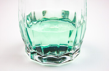 Glass with light green,aquamarine alcoholic beverage on white background.