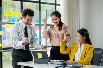Three people are celebrating a success in a business meeting