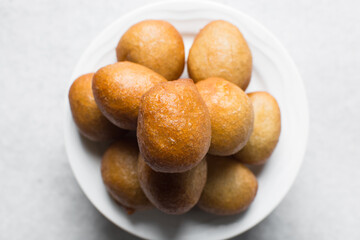 overhead view of nigerian puff-puff on a white plate, flatlay of nigerian fried dough balls, homemade bofrot on white dish