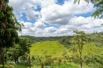 Tropical rural panorama. Trees. Mountains. Beautiful blue sky with clouds. Horizontal.