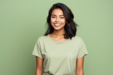 Fototapeta premium Portrait of a satisfied indian woman in her 20s dressed in a casual t-shirt isolated in pastel green background