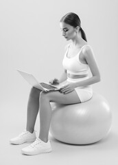Obraz premium Slender dark-skinned female blogger in a white tracksuit against a white background. Healthy lifestyle, sports and diet.