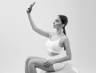 Naklejka premium Slender dark-skinned female blogger in a white tracksuit against a white background. Healthy lifestyle, sports and diet.