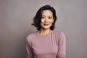 Obraz premium Portrait of a content asian woman in her 40s donning a classy polo shirt isolated in pastel gray background