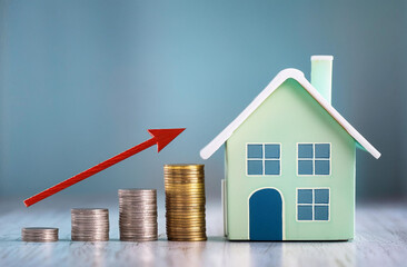 Model home with increasing stacks of coins and arrow,  real estate market and home prices concept, copy space