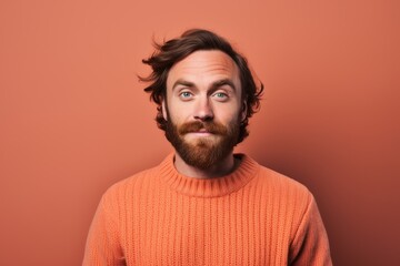 Obraz premium Portrait of a satisfied man in his 30s dressed in a warm wool sweater while standing against pastel brown background