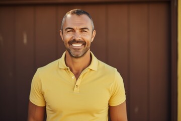 Portrait of a smiling man in his 40s donning a classy polo shirt in front of soft yellow background