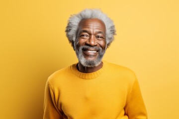 Obraz premium Portrait of a glad afro-american man in his 70s showing off a thermal merino wool top while standing against soft yellow background