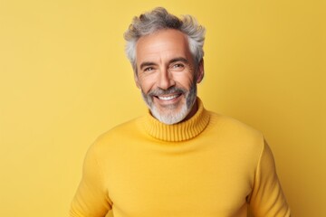 Obraz premium Portrait of a satisfied man in his 60s showing off a thermal merino wool top in soft yellow background