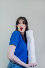 Young woman with toilet paper on gray background, woman saving a lot of toilet paper at home. The...