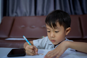 Cute Little boy writing in book at home,education, childhood, people, homework and school concept.