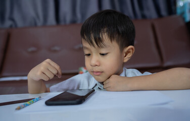 Cute little boy watching videos,relaxing at home.little boy looking at the phone, close-up. little boy use of smart phone.