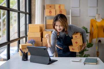 A woman is standing in front of a large stack of boxes, holding them up