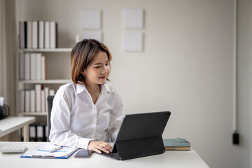 A woman is sitting at a desk with a laptop and a book