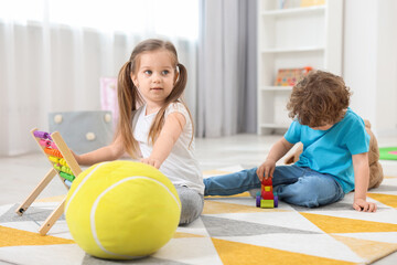 Fototapeta premium Cute little children playing with different toys on floor in kindergarten