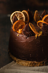 Detail of a chocolate and orange cake beautifully decorated. Chocolate cake decorated with slices of baked orange on a dark brown background. 