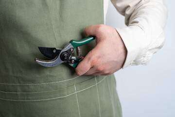 A man holds a garden pruner in his hands. A set of gardening tools for caring for plants in the...