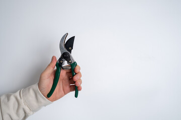 A man holds a garden pruner in his hands. A set of gardening tools for caring for plants in the garden or at home. Florist and gardening care concept