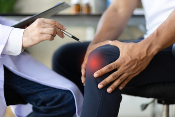 Doctor diagnoses the cause of osteoarthritis and knee pain of a male patient in an examination room...