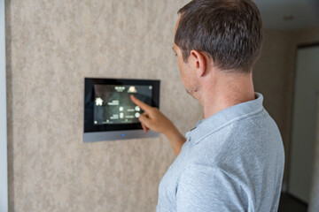 Man using tablet panel application for control smart home living. Wireless device controller for...