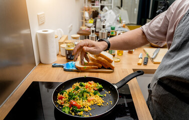 Chef at the kitchen preparing tofu scramble with vegetables