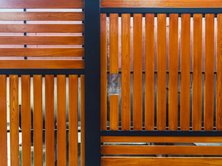Fototapeta premium Broken shera wood board fence. Hole in wooden wall. Damaged weathered brown picket fence with broken rails and planks. A broken plank on the fence. Wooden wall with broken boards. Broken fence.