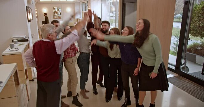 In a display of unity and teamwork, a cohesive group of business professionals in casual office attire join hands, showcasing their commitment to working together towards common goals.