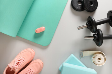Sport, yoga and fitness equipment, pink shoes, belt, foam, blocks for pilates, dumbbells on gray background. Top view. Copy space. © svetlana_cherruty