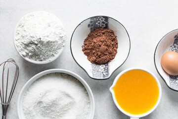 mise en place of ingredients for making brownies, top view of sugar, eggs, butter, flour cocoa powder on a marble table, process of making brownies