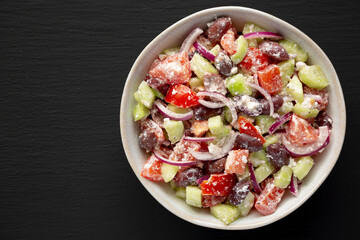 Homemade Chopped Mediterranean Salad in a Bowl on a black background, top view.