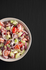 Homemade Chopped Mediterranean Salad in a Bowl on a black background, top view.