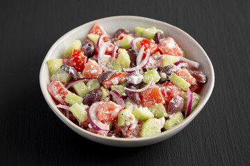 Homemade Chopped Mediterranean Salad in a Bowl on a black background, side view.