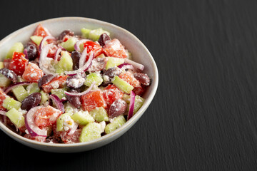 Homemade Chopped Mediterranean Salad in a Bowl on a black background, side view. Copy space.