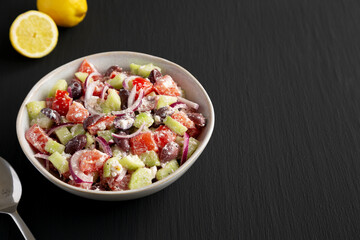 Homemade Chopped Mediterranean Salad in a Bowl on a black background, side view. Copy space.