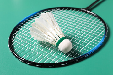 Feather badminton shuttlecock and racket on green background, closeup