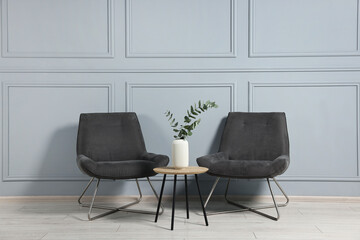 Comfortable armchairs, side table and eucalyptus indoors