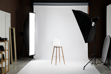 White photo background, chair and professional lighting equipment in studio