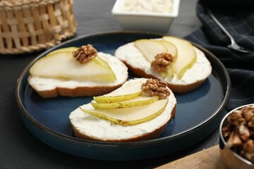 Delicious bruschettas with ricotta cheese, pears and walnuts on dark table, closeup